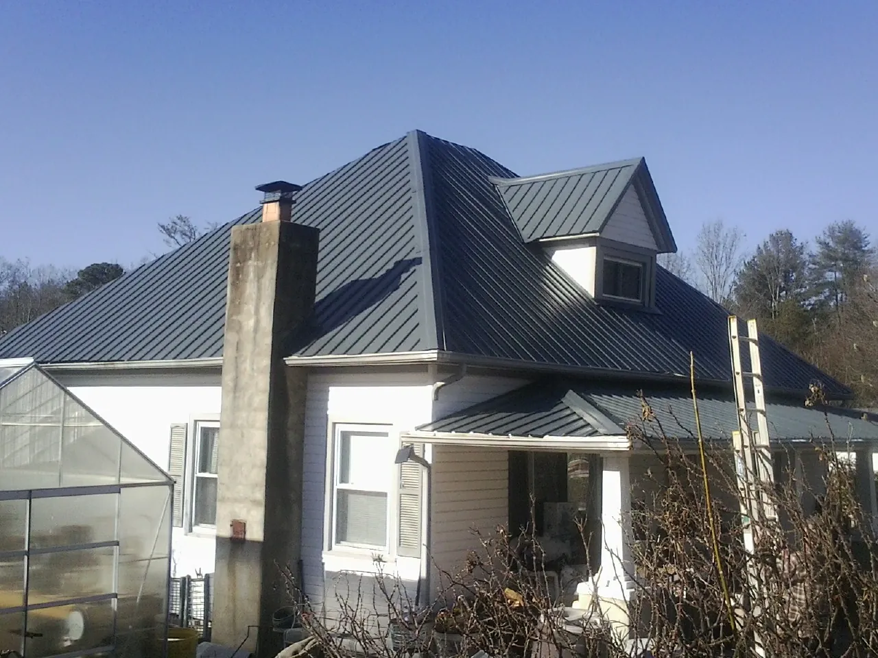 Dark blue standing seam metal roof on a white farmhouse with dormer — Slate & Tile Roof Repair by Roofing Brothers in Nanticoke