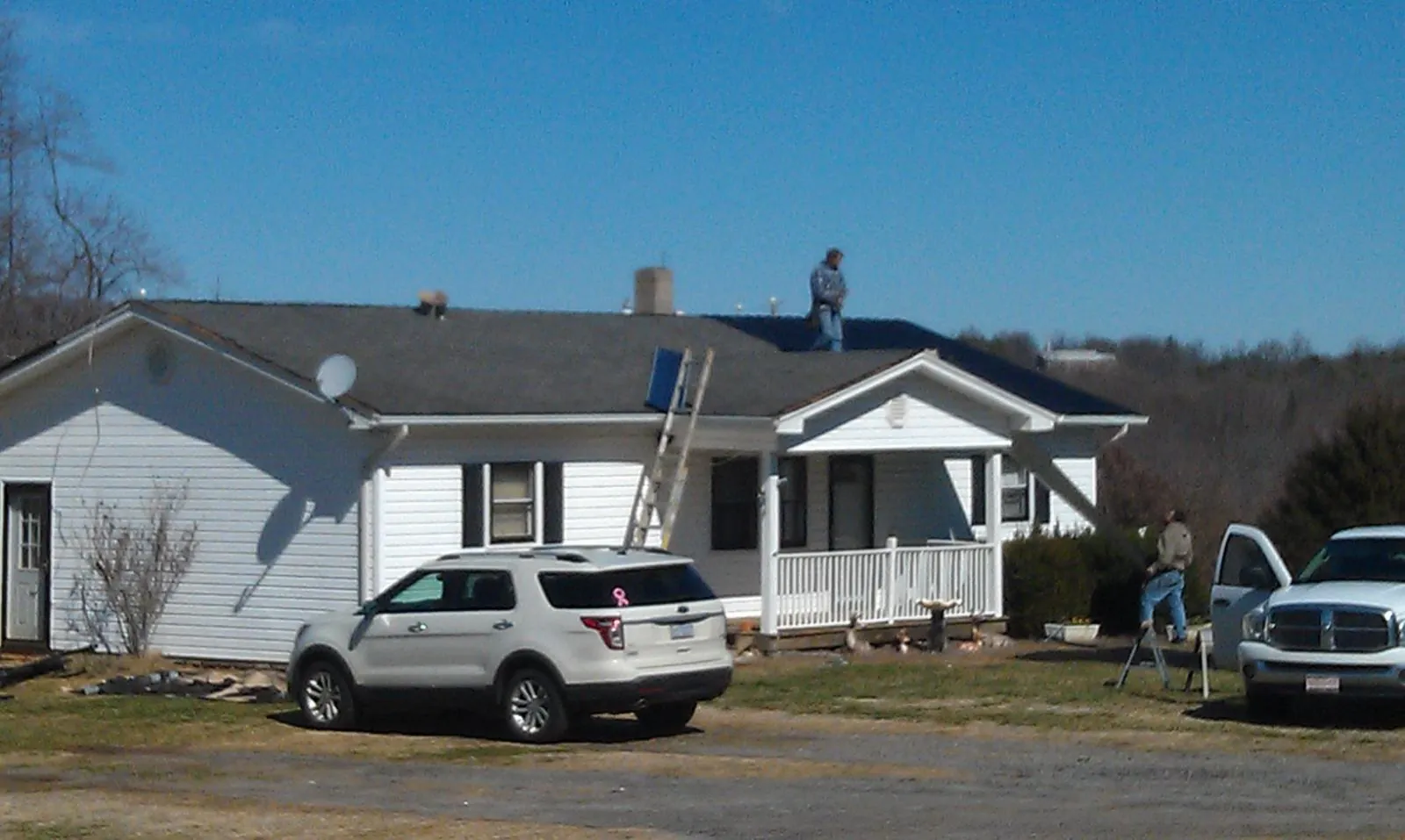 Roofers stripping shingles from a white ranch house roof in Nanticoke